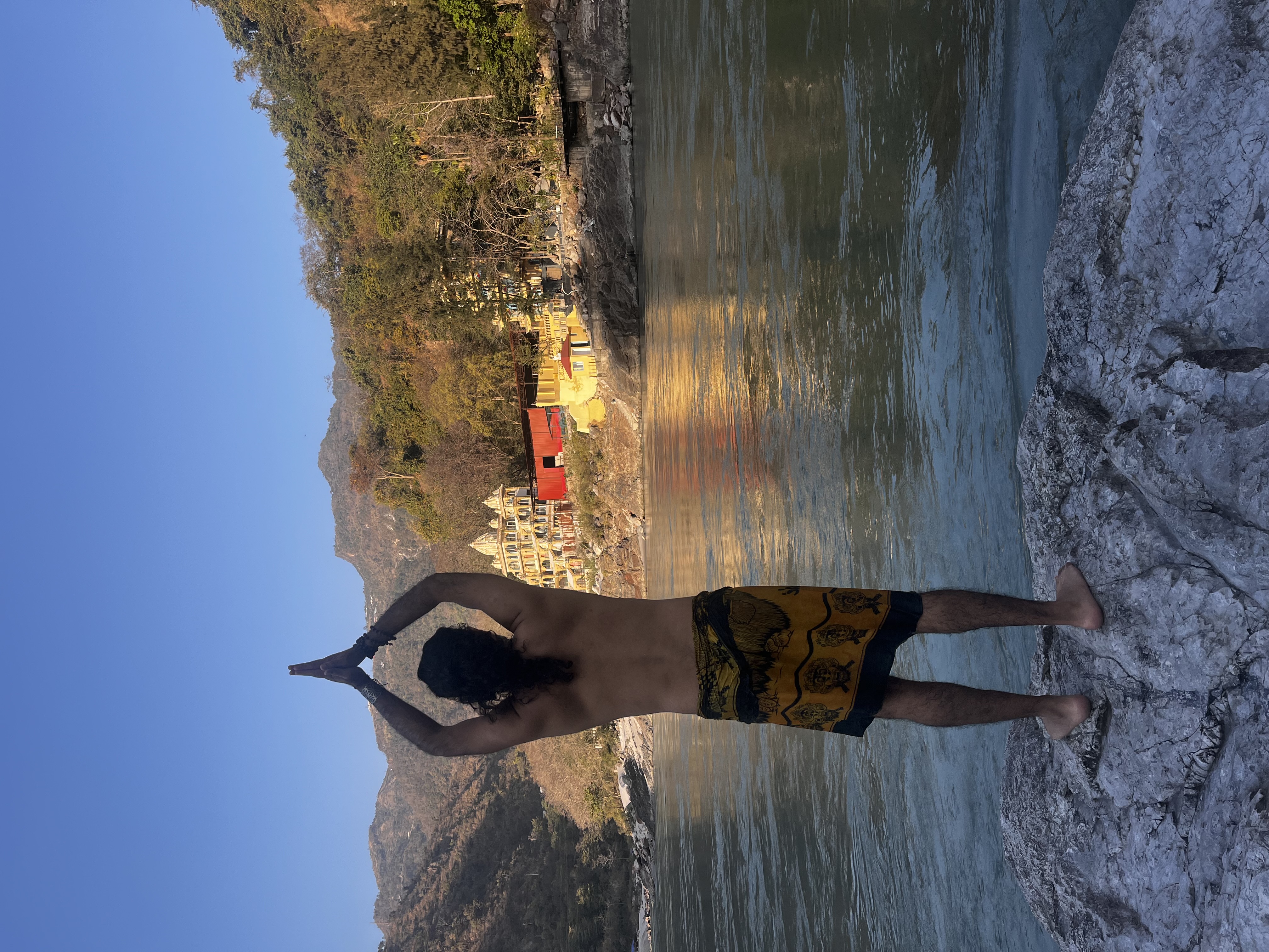 Yogi Rohan facing the river and mountains in meditation